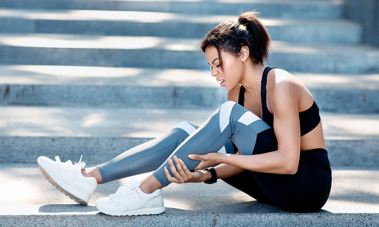 A woman with a hamstring injury holding her leg, considering treatment options like PowerCure Pro cold laser therapy