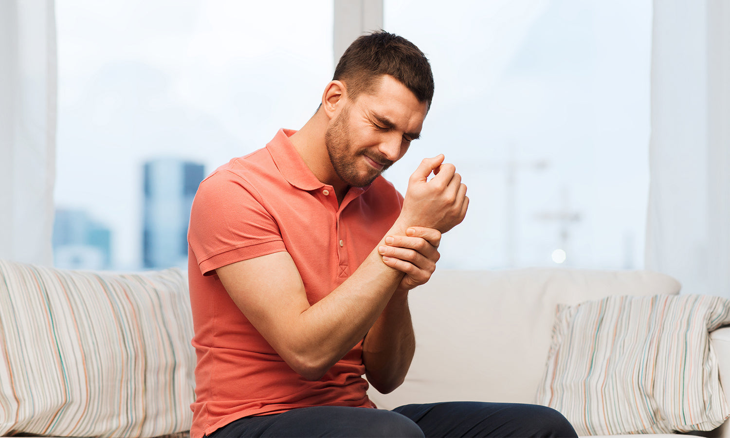 Man holding his wrist in pain from rheumatoid arthritis, considering treatment with PowerCure laser therapy