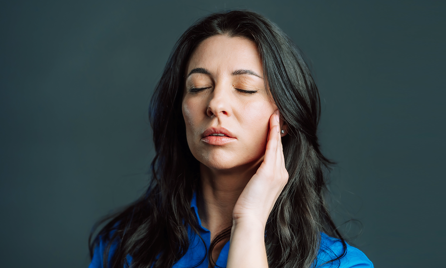 A woman touching her face in pain from trigeminal neuralgia